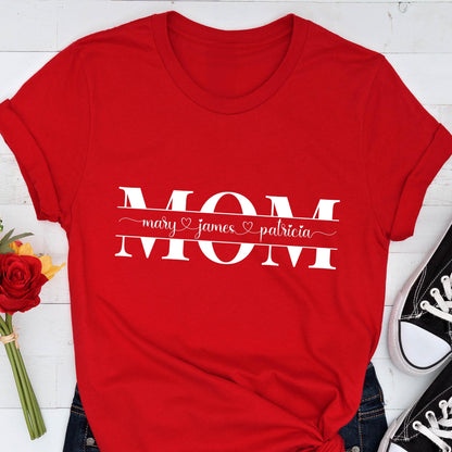May include: Red t-shirt with the word "MOM" in white letters with a banner underneath that reads "mary ♥ james ♥ patricia".
