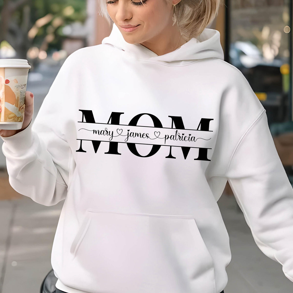 May include: White hooded sweatshirt with the word "MOM" in black letters and the names "mary", "james", and "patricia" written below in a cursive font.