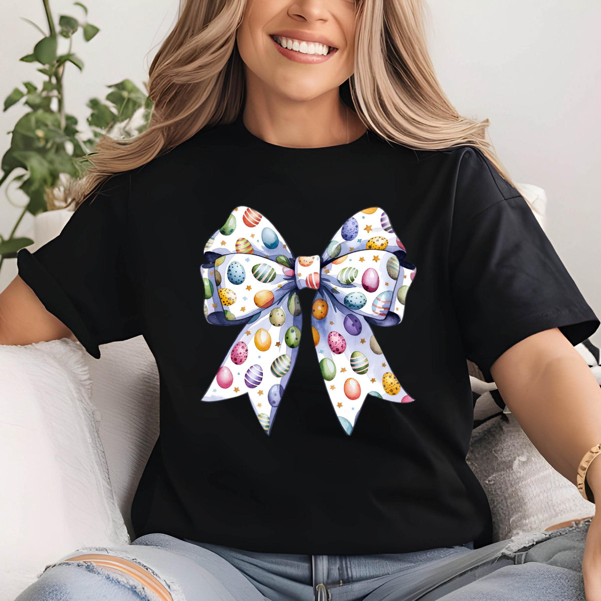 May include: Black t-shirt with a large white bow printed on the front. The bow is decorated with colorful Easter eggs.
