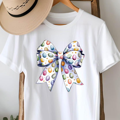 May include: White t-shirt with a large blue bow printed on the front. The bow is decorated with colorful Easter eggs.