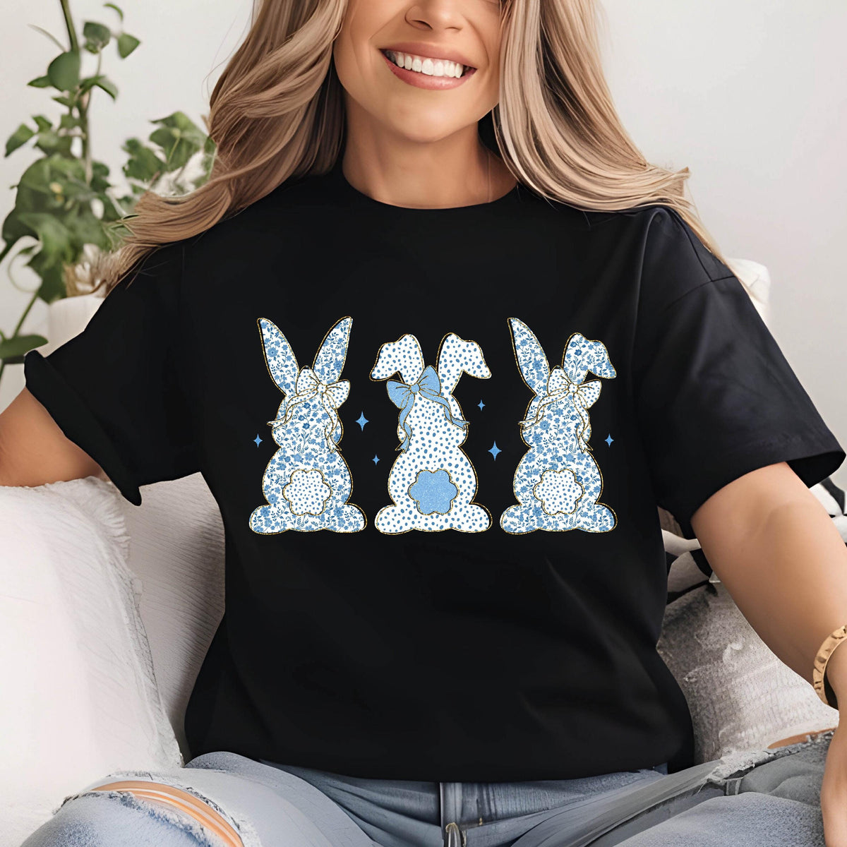 May include: Black t-shirt with a graphic of three blue bunnies with white polka dots and blue bows. The bunnies are facing away from the viewer.