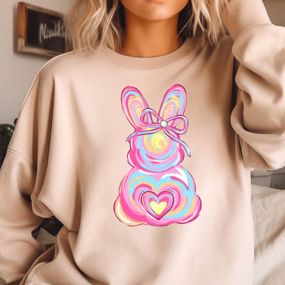 May include: A light brown sweatshirt with a pink, blue, and yellow swirl design of an Easter bunny with a pink bow. The bunny has a heart shape in the center.
