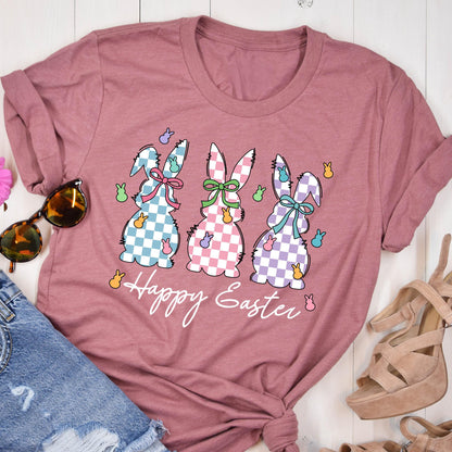 May include: A pink t-shirt with a graphic of three checkered Easter bunnies with bows and the text "Happy Easter".