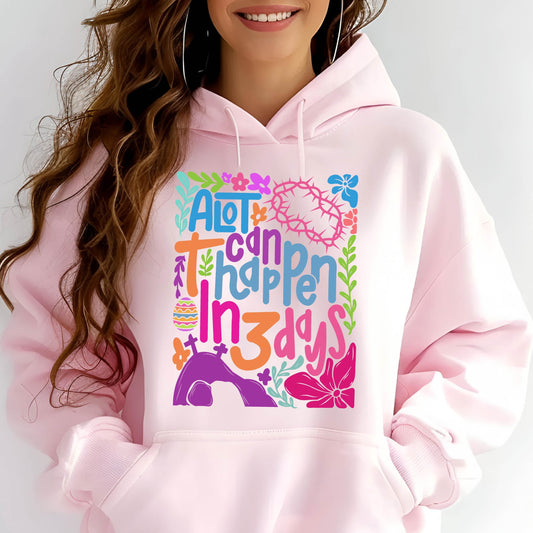May include: Pink hoodie with a colorful graphic design that says "A lot can happen in 3 days". The graphic includes flowers, a cross, a crown of thorns, and an Easter egg.