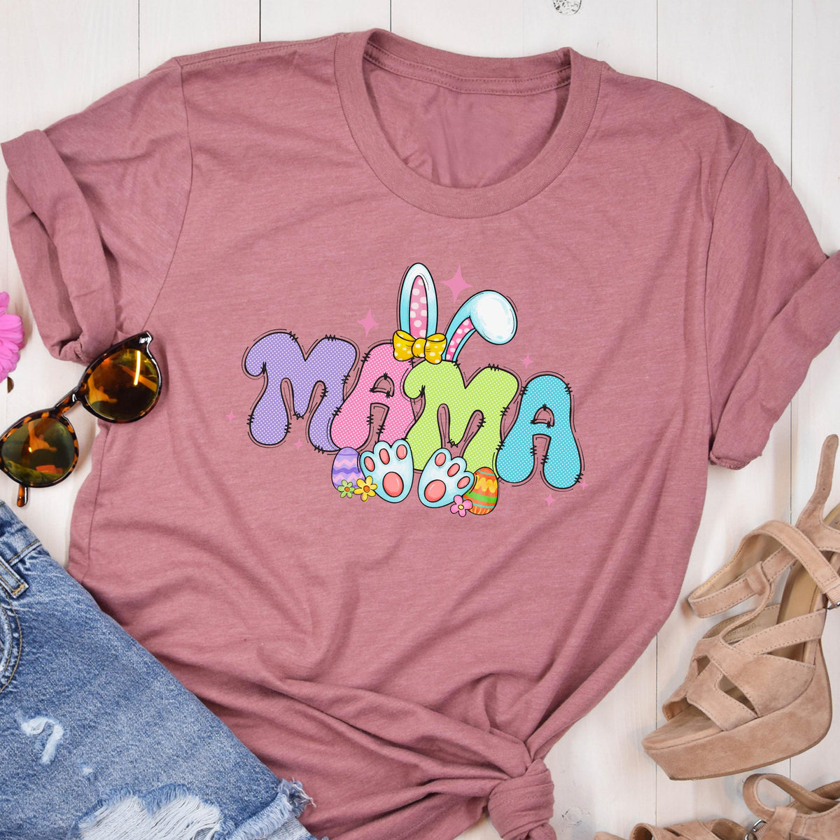 May include: A pink t-shirt with a colorful graphic of the word "MAMA" with bunny ears and Easter eggs. 