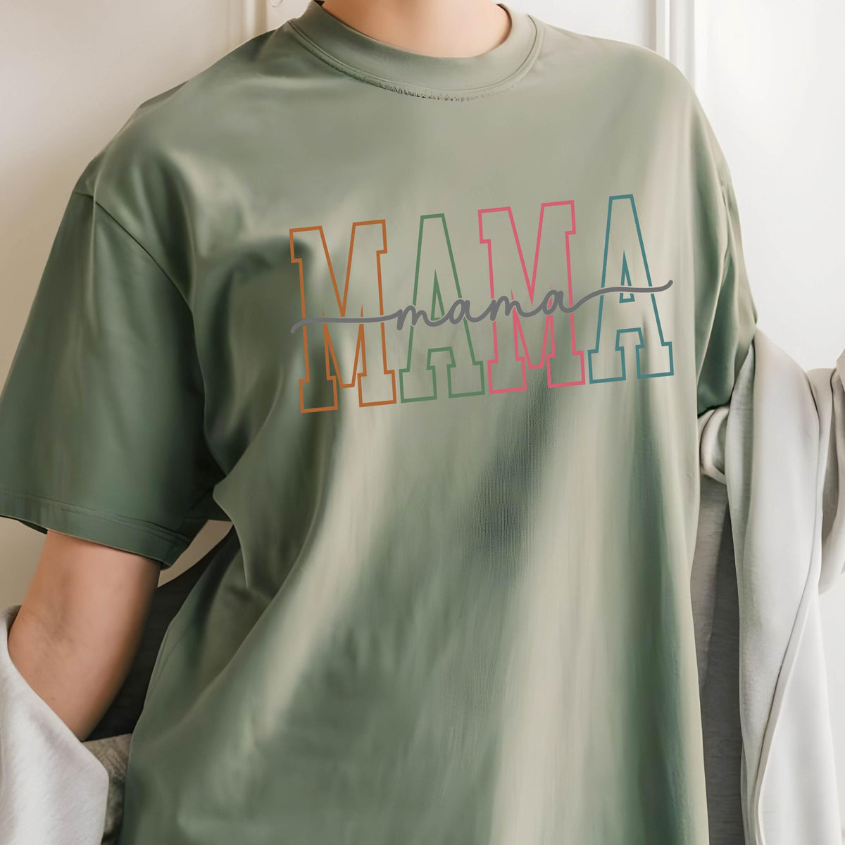 May include: A green t-shirt with the word "MAMA" in colorful block letters and the word "mama" written in cursive underneath.