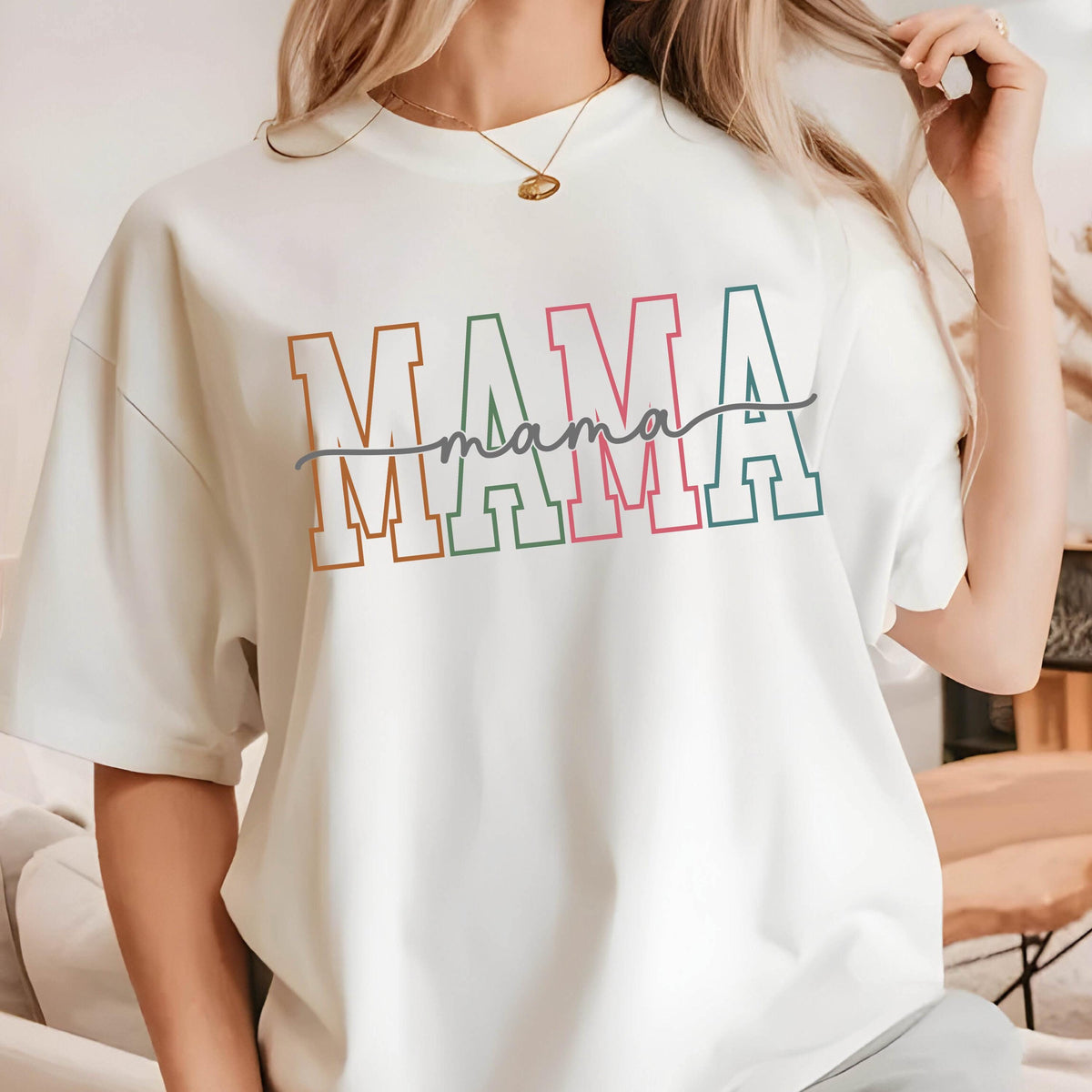 May include: White t-shirt with the word "MAMA" in colorful block letters with a handwritten "mama" underneath.