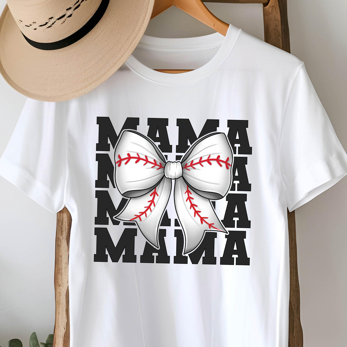 May include: White t-shirt with a black graphic of the word "MAMA" repeated four times with a white baseball-stitched bow in the center.