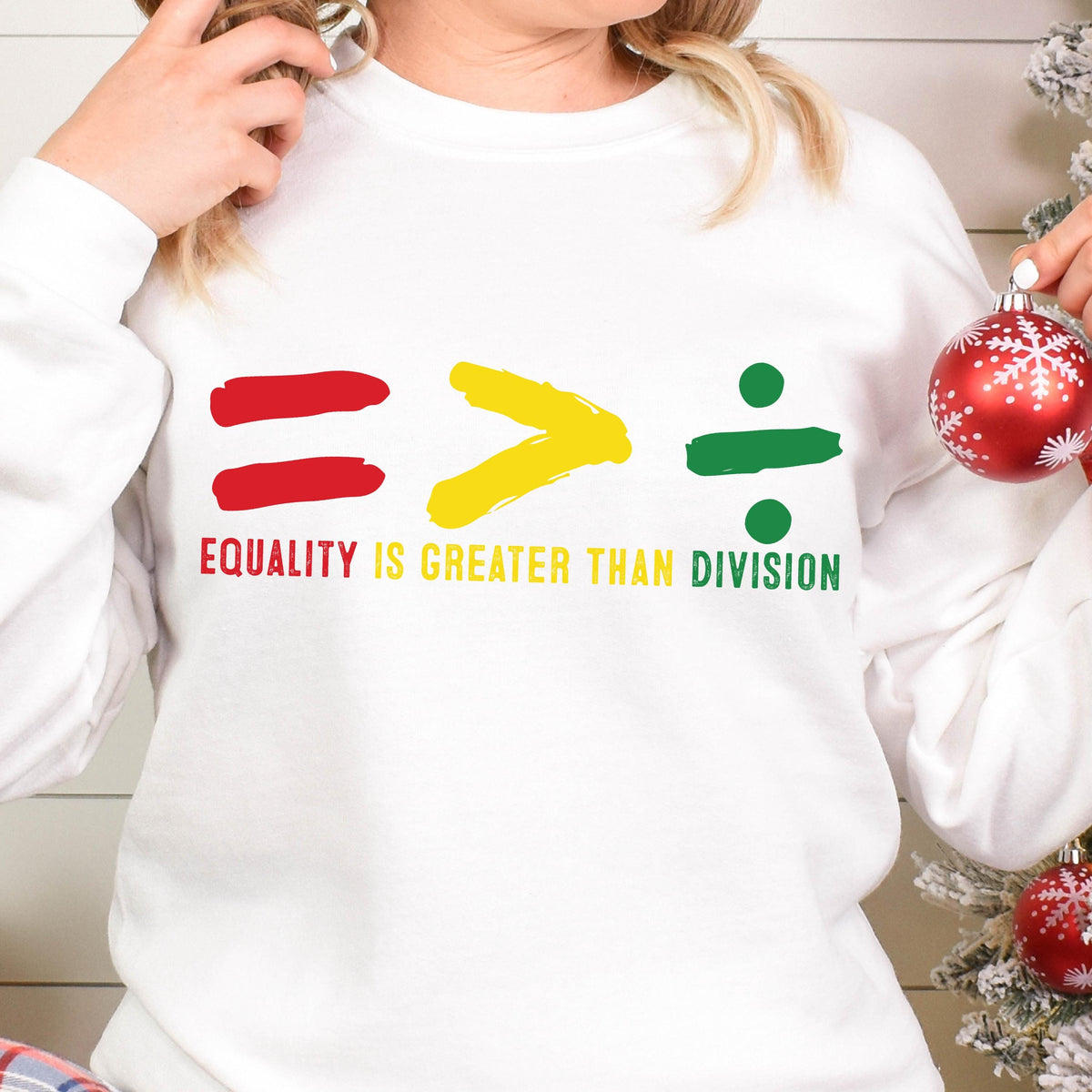 May include: White sweatshirt with a red equals sign, a yellow greater than sign, and a green division sign. The text "Equality is greater than division" is printed below the symbols.