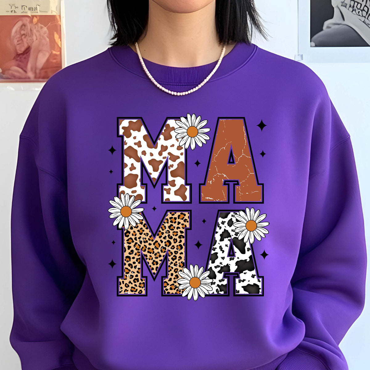 May include: Purple sweatshirt with a graphic print of the word "MAMA" in large letters. The letters are decorated with cow print, leopard print, and daisies.