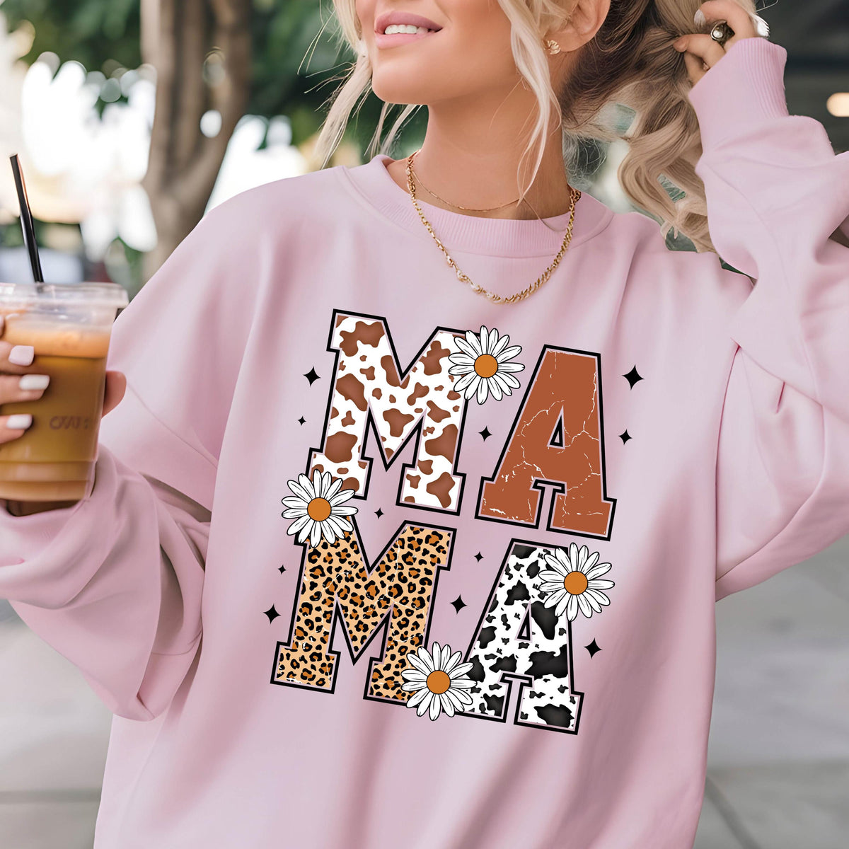 May include: Pink sweatshirt with the word "MAMA" printed in large letters. Each letter is decorated with a different animal print: cow, leopard, and cow. The letters are surrounded by white daisies.