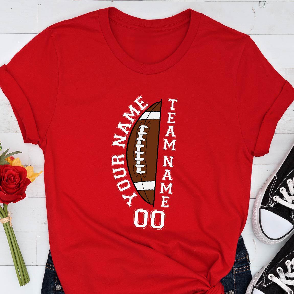 May include: A bright red short-sleeved t-shirt featuring a graphic of a brown football split in half. The text "YOUR NAME" and "TEAM NAME" is printed in white vertically along the sides of the football, with the number "00" printed below.