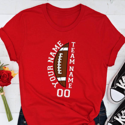 May include: A bright red short-sleeved t-shirt featuring a graphic of a brown football split in half. The text "YOUR NAME" and "TEAM NAME" is printed in white vertically along the sides of the football, with the number "00" printed below.