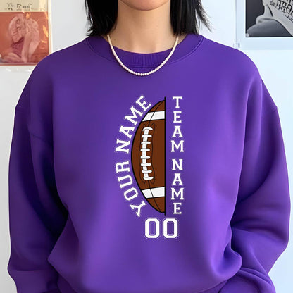 May include: A purple sweatshirt featuring a football design. The football graphic is brown and white, with the words "YOUR NAME" and "TEAM NAME" in white, along with the number "00". The sweatshirt is a solid purple color.