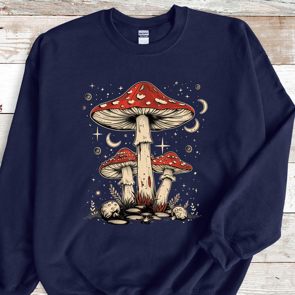 May include: Navy blue sweatshirt with a graphic of three red and white mushrooms with white spots. The mushrooms are surrounded by white stars and crescent moons. 