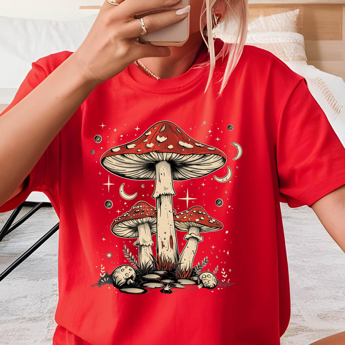 May include: Red t-shirt with a graphic of three mushrooms with white spots and a starry night sky background.