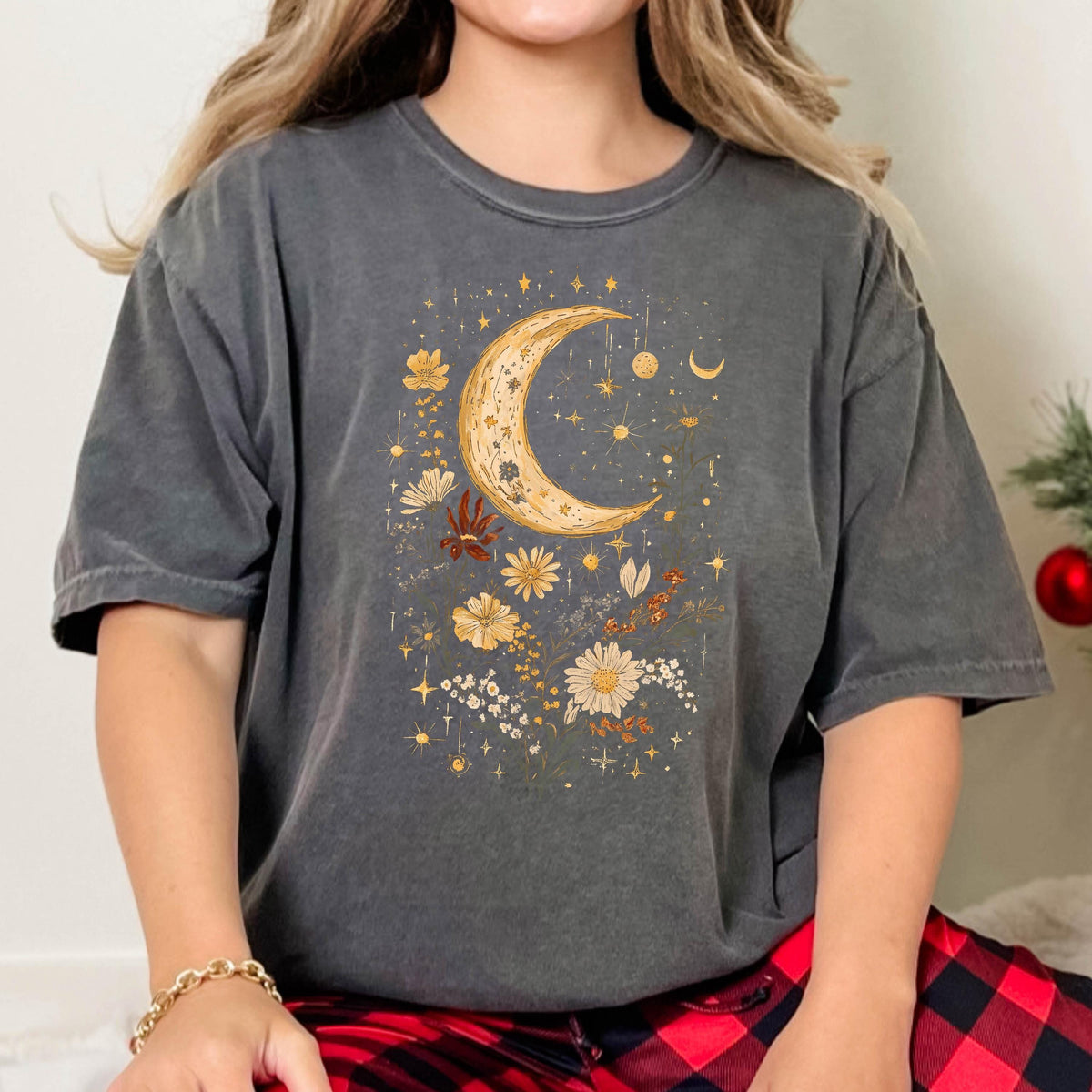 May include: A charcoal gray t-shirt with a crescent moon and floral design in gold and yellow. The design features a crescent moon with stars and flowers.