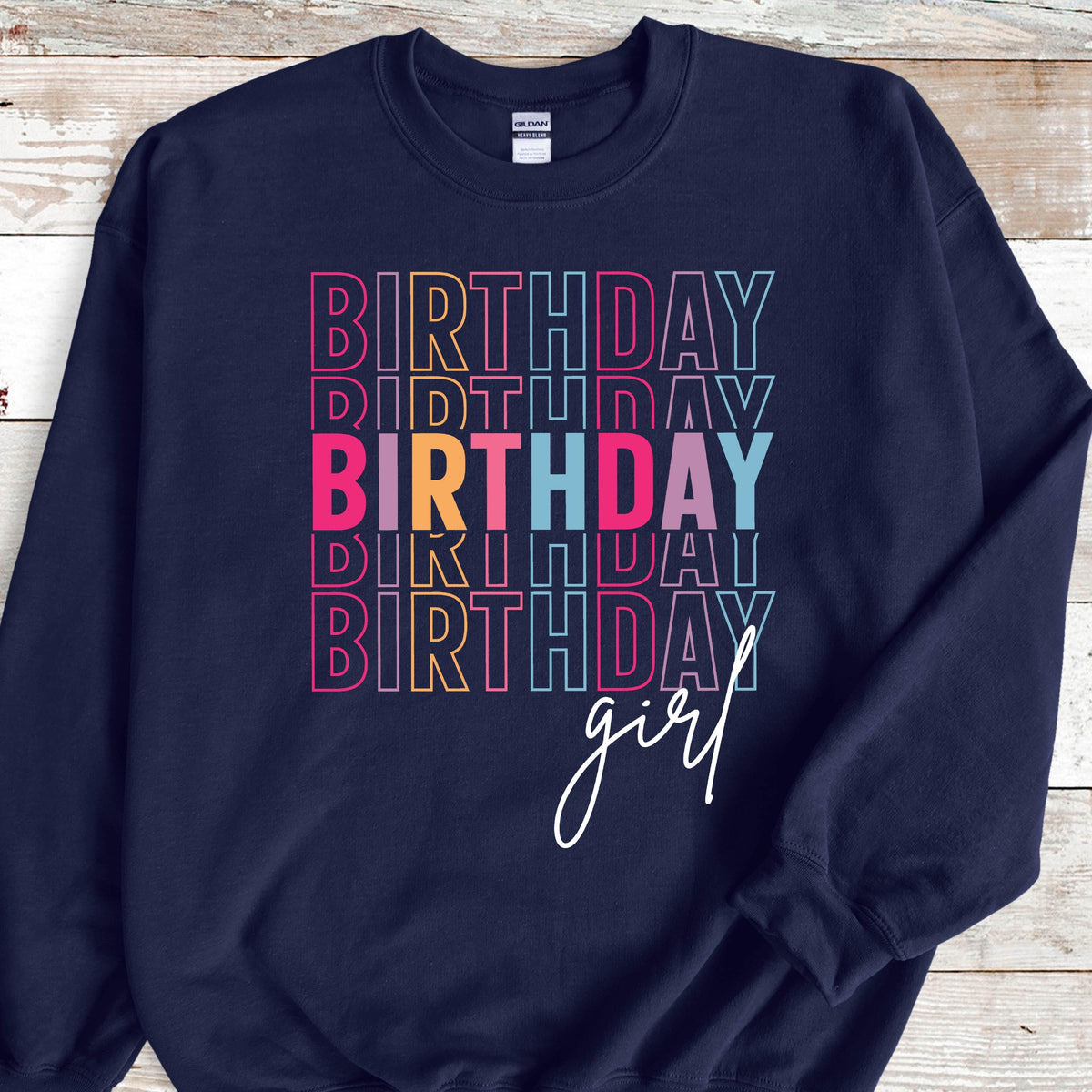 May include: Navy blue sweatshirt with the text "Birthday girl" in rainbow colors. The word "Birthday" is stacked on top of itself four times.