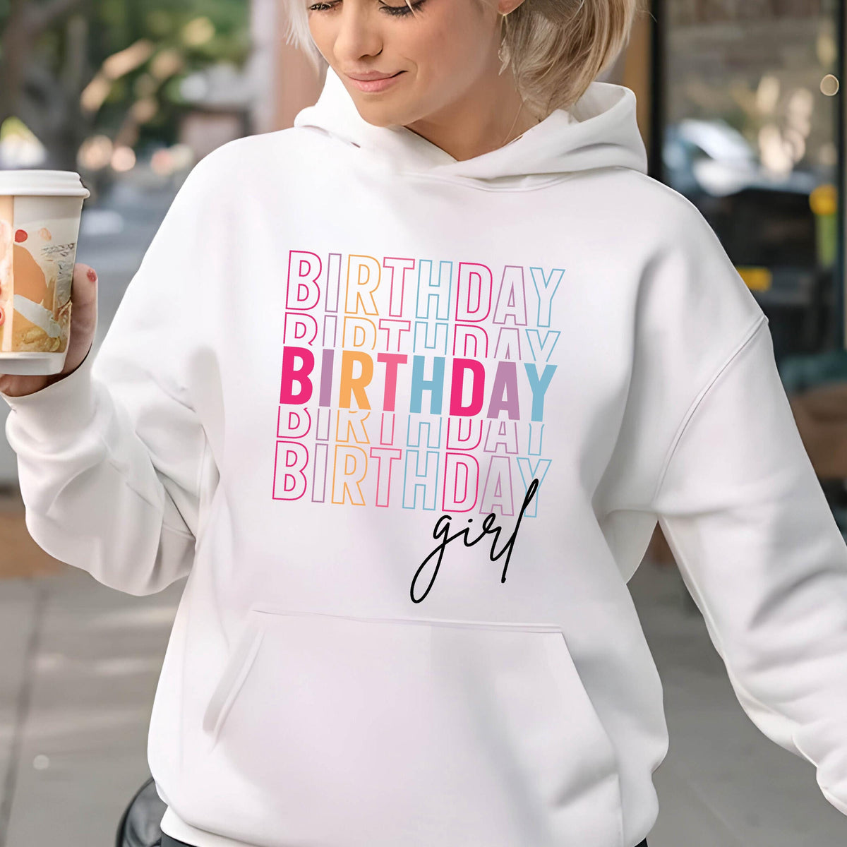 May include: White hoodie with the text "Birthday girl" in rainbow colors. The text is stacked and repeated multiple times.