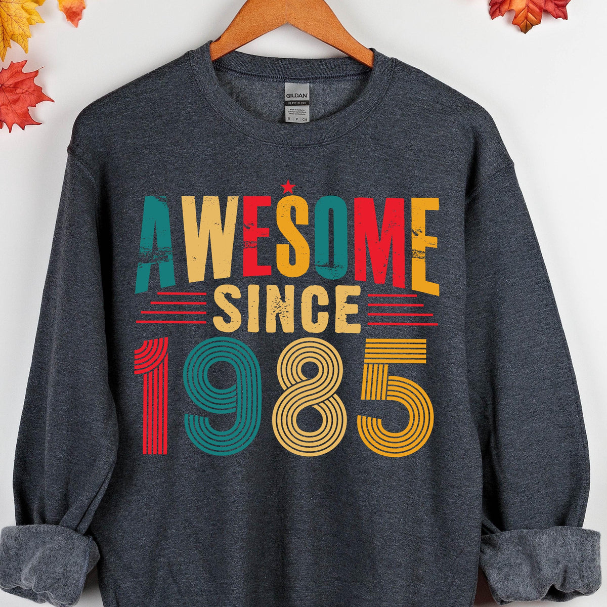 May include: A dark gray sweatshirt with the text "Awesome Since 1985" in colorful retro-style lettering.