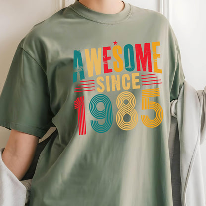 May include: Green t-shirt with a vintage-style graphic that says "Awesome Since 1985" in red, yellow, blue, and green.