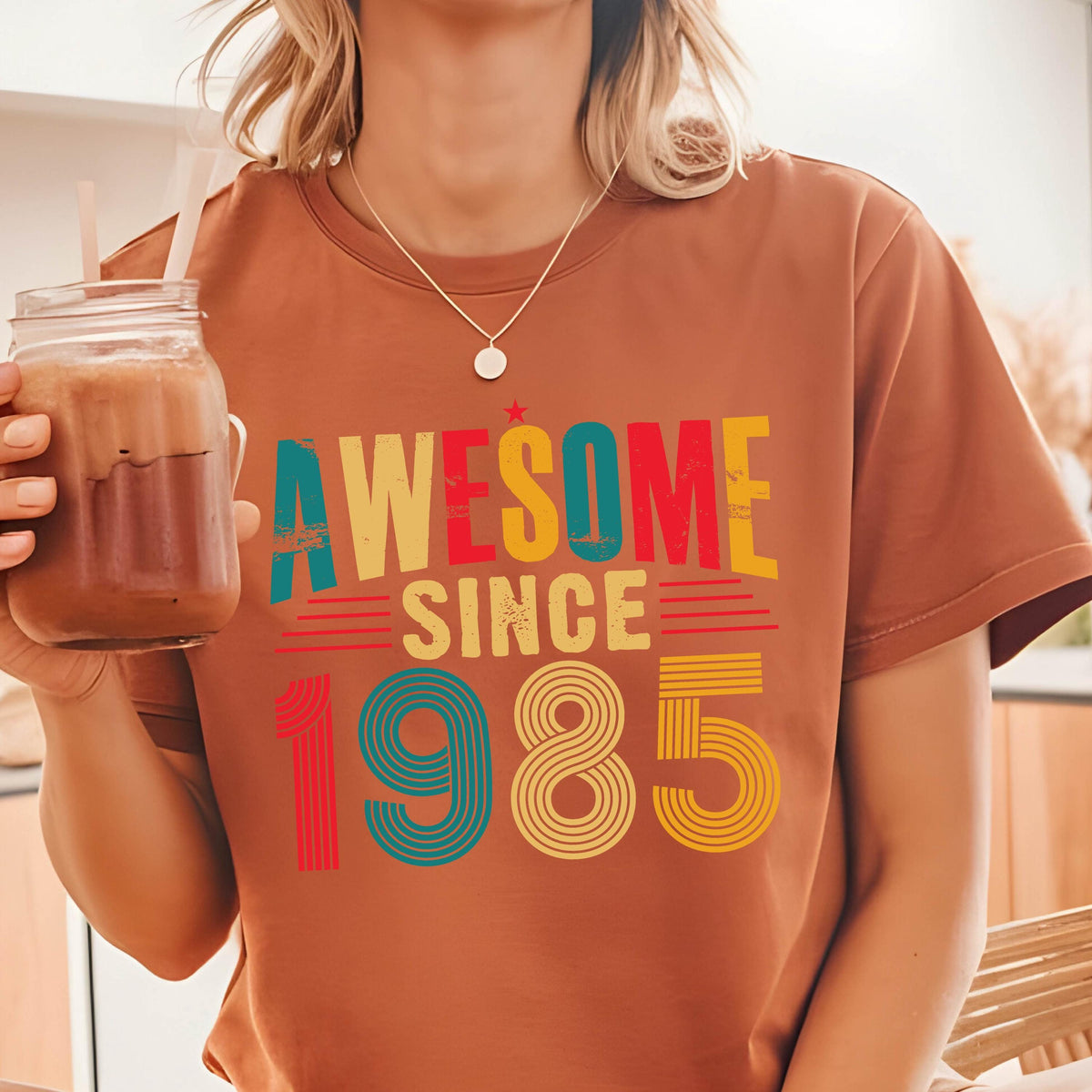 May include: A brown t-shirt with a retro-style graphic that says "Awesome Since 1985" in colorful letters.