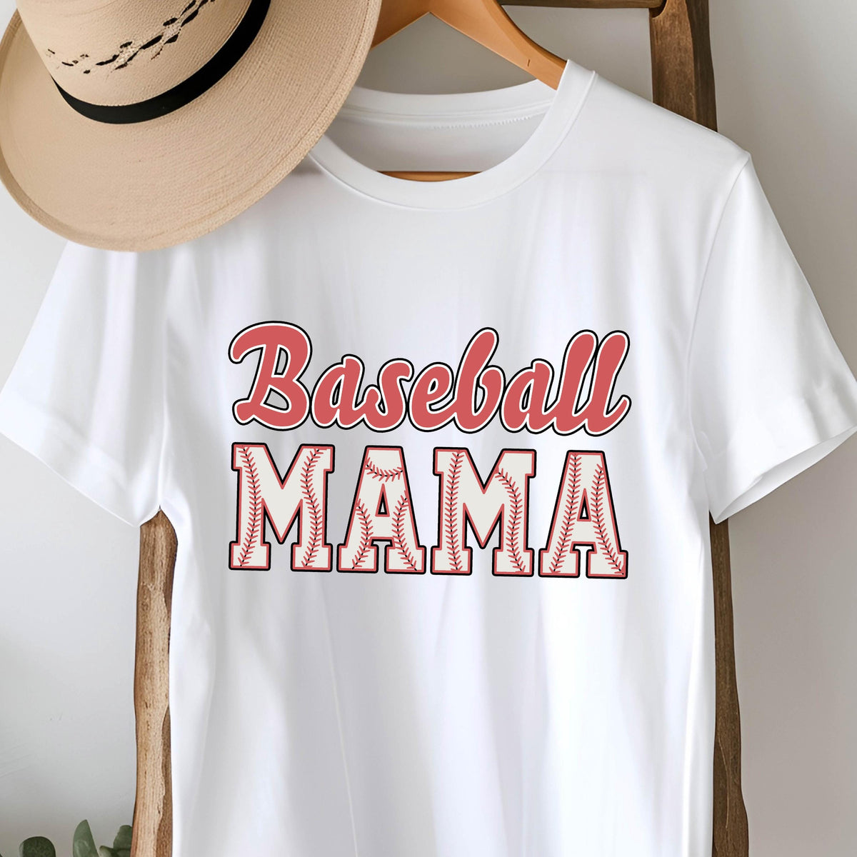 May include: White t-shirt with the text "Baseball Mama" in red lettering. The letters are outlined in black and have a baseball stitching pattern.