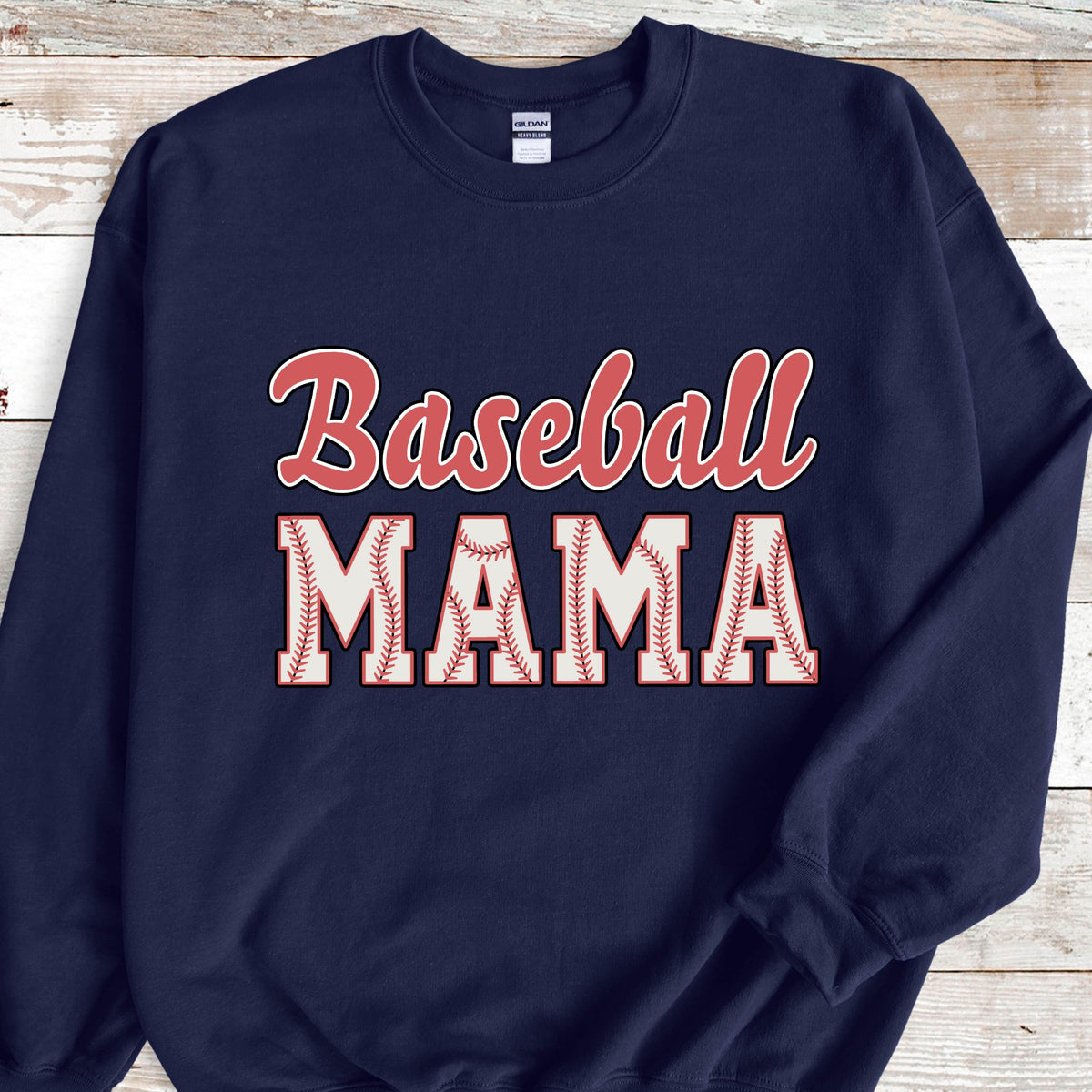 May include: A navy blue crewneck sweatshirt featuring the text Baseball MAMA printed on the front. The word Baseball is in a red script font, while the word MAMA is in large white block letters with a red baseball stitch pattern design.