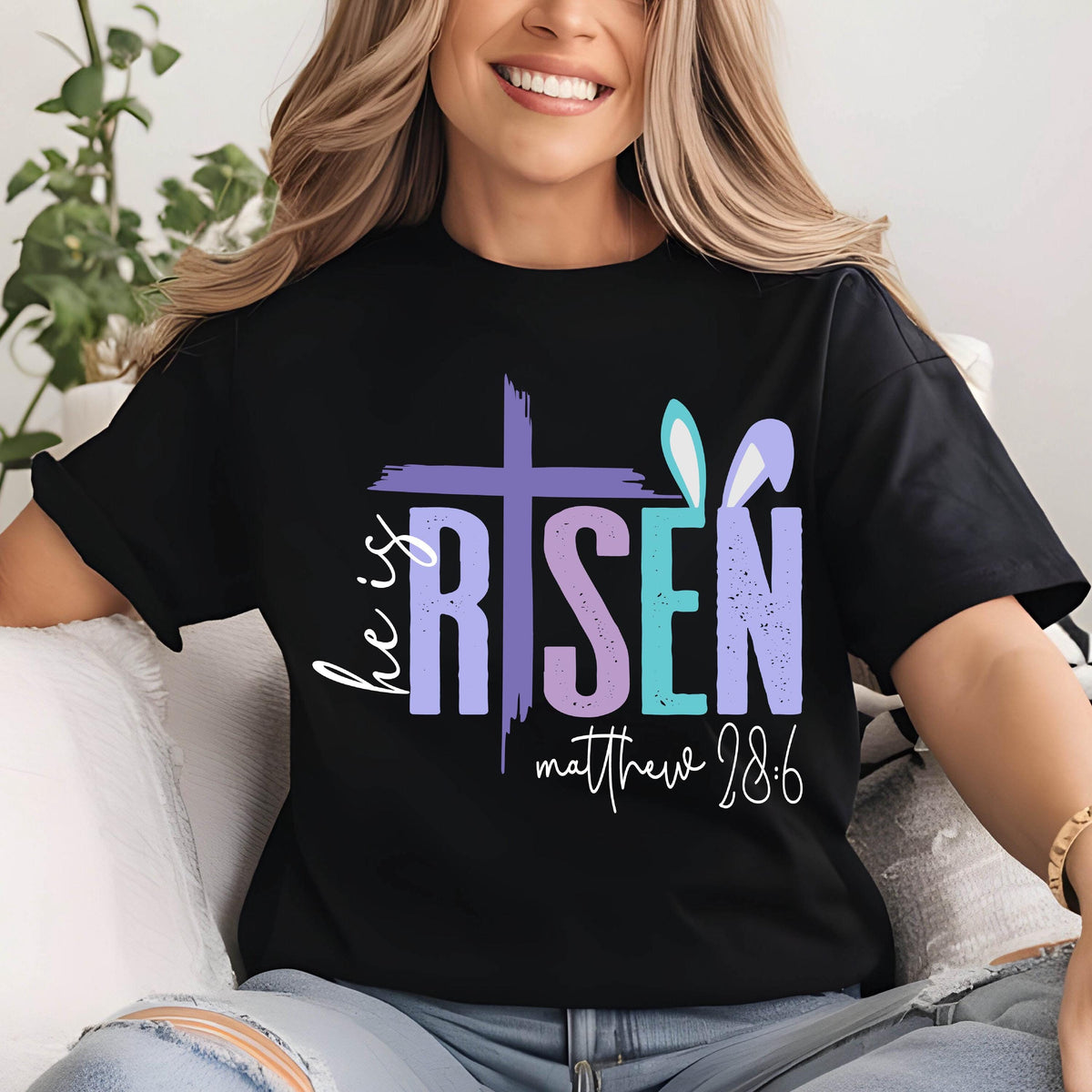 May include: Black t-shirt with a colorful graphic that says "He is Risen" with a cross and bunny ears. The text "Matthew 28:6" is below the graphic.