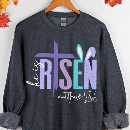 May include: A dark gray sweatshirt with a purple, pink, and blue graphic that says "He is Risen" with bunny ears and the text "Matthew 28:6".
