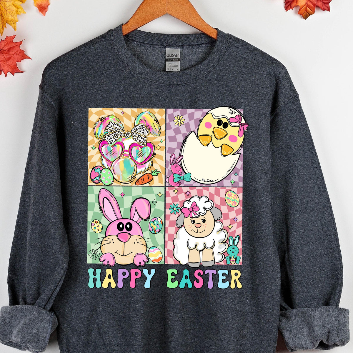 May include: A dark grey sweatshirt with a colorful graphic print of four Easter animals. The animals are a bunny, a chick, a lamb, and a rabbit. The graphic is surrounded by a colorful border and the text "Happy Easter" is printed below the graphic.