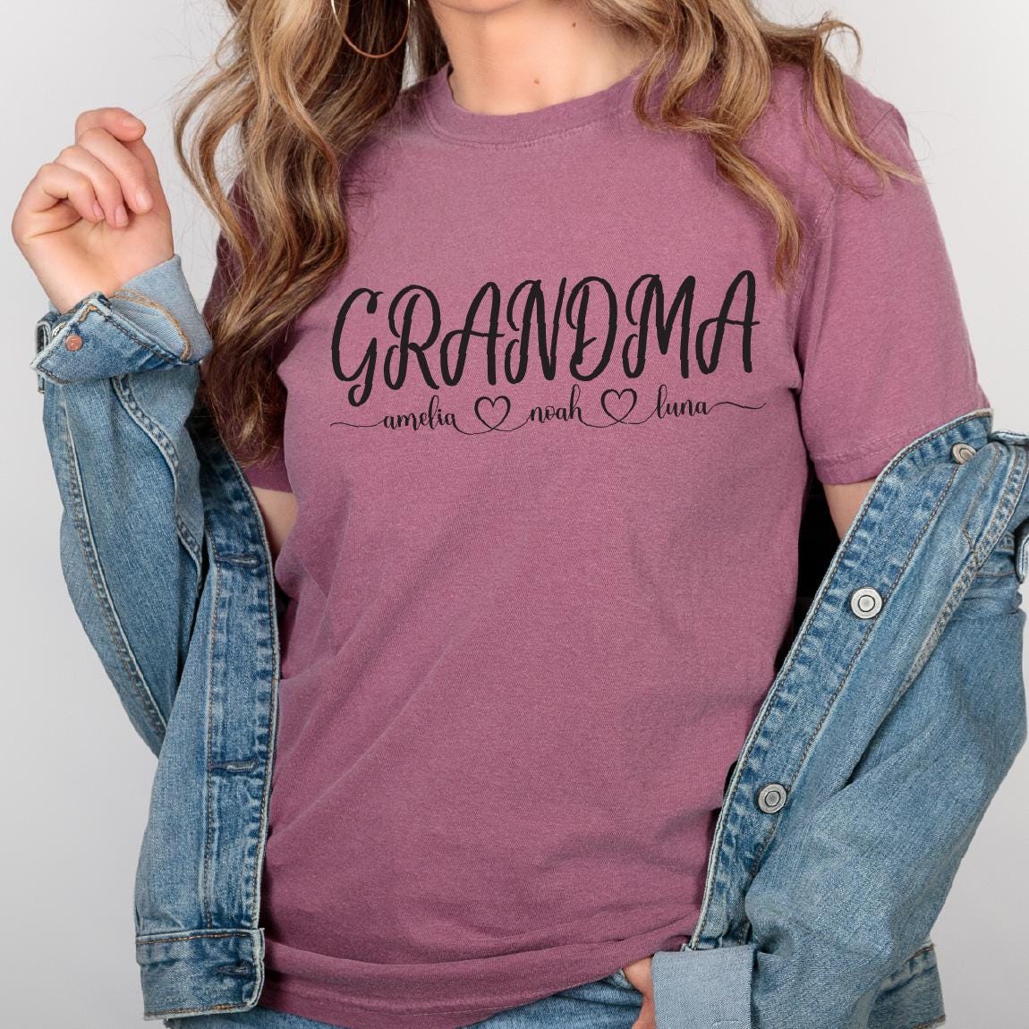 May include: A mauve t-shirt with the text "Grandma" in black cursive lettering. Below the text, it says "amelia ♥ noah ♥ luna" in smaller black lettering.