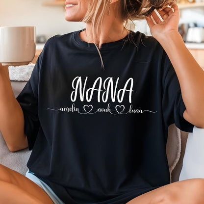 May include: Black t-shirt with the word "NANA" in white cursive lettering. Below the word "NANA" are the names "amelia", "noah", and "luna" in white lettering with a heart symbol between each name.
