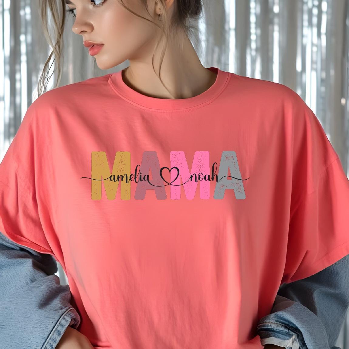 May include: A pink t-shirt with the word "MAMA" in colorful letters. The letters are decorated with a heart and the names "Amelia" and "Noah" written in cursive.