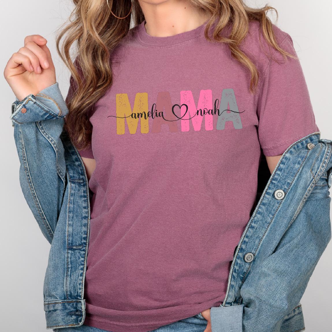 May include: A mauve t-shirt with the word "MAMA" in colorful block letters. The letters are decorated with the names "Amelia" and "Noah" and a heart.