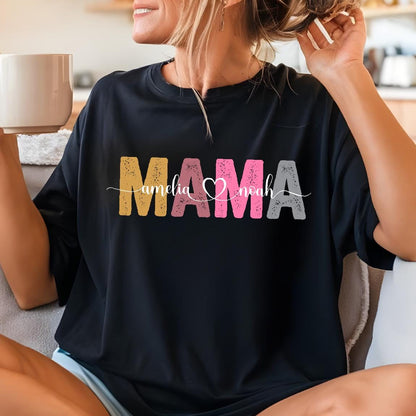 May include: Black t-shirt with the word "MAMA" in colorful block letters and the names "Amelia" and "Noah" written in cursive on either side of the word. A heart symbol is between the names.