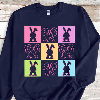 May include: Navy blue sweatshirt with a colorful design of nine squares featuring pink bows and bunny silhouettes.