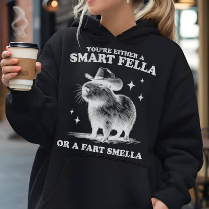 May include: Black hoodie with a graphic of a capybara wearing a cowboy hat. The text reads "You're either a Smart Fella or a Fart Smella" in white. The design includes stars.