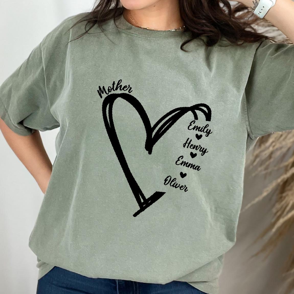 May include: A sage green short-sleeve t-shirt featuring a black graphic of a hand-drawn heart outline. The word Mother is printed above the heart, and the names Emily, Henry, Emma, and Oliver are listed vertically with small hearts in between.