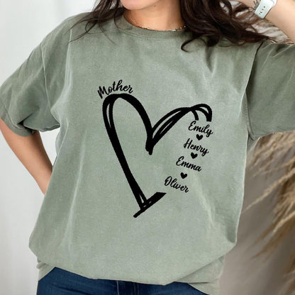 May include: A sage green short-sleeve t-shirt featuring a black graphic of a hand-drawn heart outline. The word Mother is printed above the heart, and the names Emily, Henry, Emma, and Oliver are listed vertically with small hearts in between.