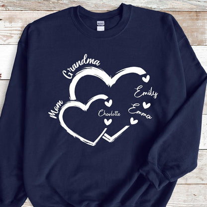 May include: Navy blue sweatshirt with a white design of two interlocking hearts. The text "Grandma" is above the hearts, and the text "Mom" is to the left of the hearts. Inside the hearts are the names "Charlotte", "Emily", and "Emma".