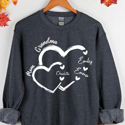 May include: A dark gray sweatshirt with a white design of two intertwined hearts. The text "Grandma" is above the hearts, and the names "Mom", "Emily", "Emma", and "Charlotte" are inside the hearts.