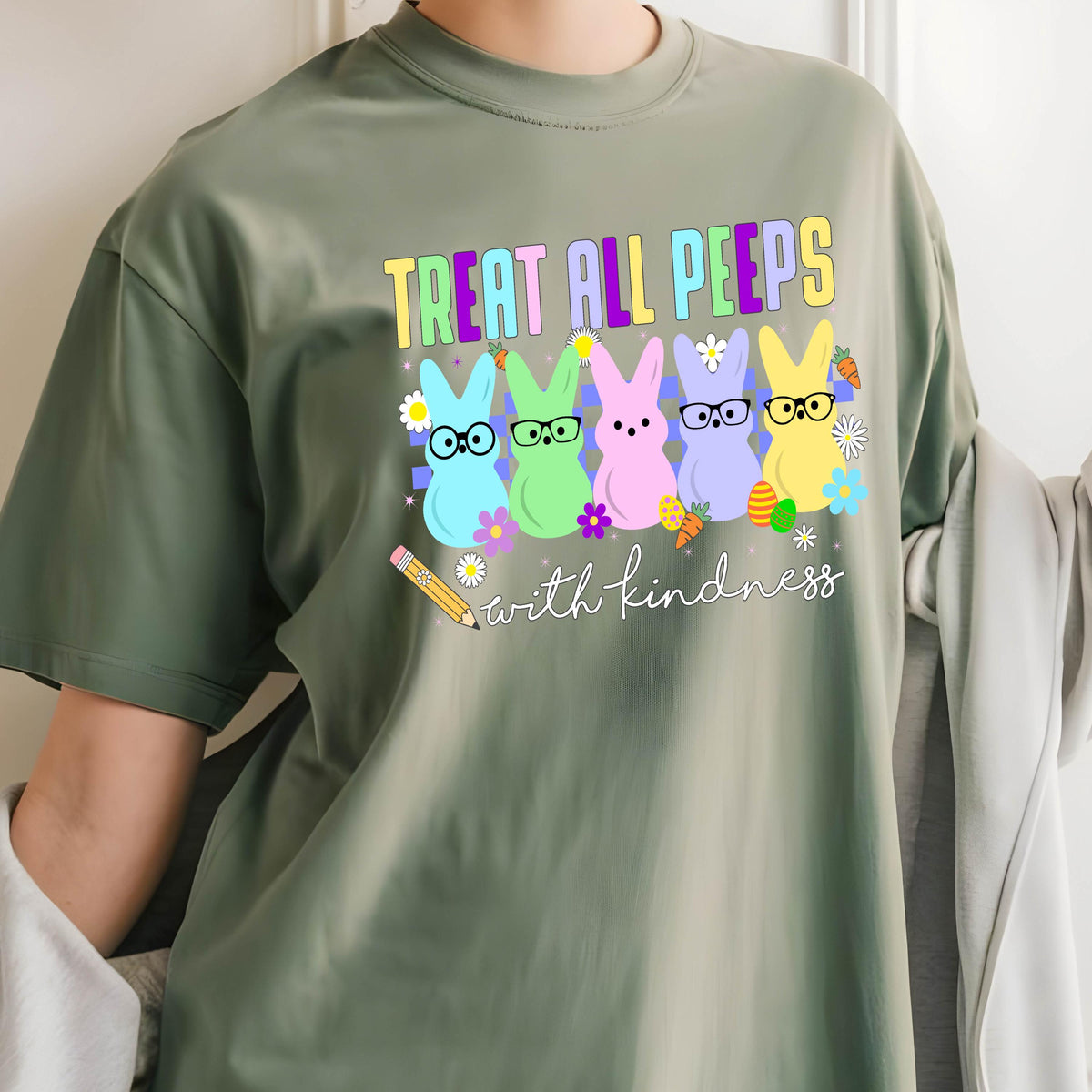 May include: Green t-shirt with a graphic of five pastel-colored Peeps with glasses and the text "Treat all peeps with kindness".