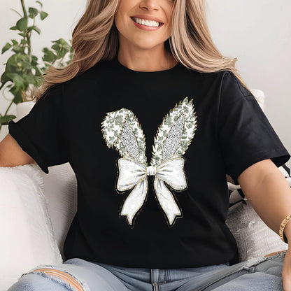 May include: Black t-shirt with a white bow and two green and white bunny ears. The bow is embellished with gold glitter.