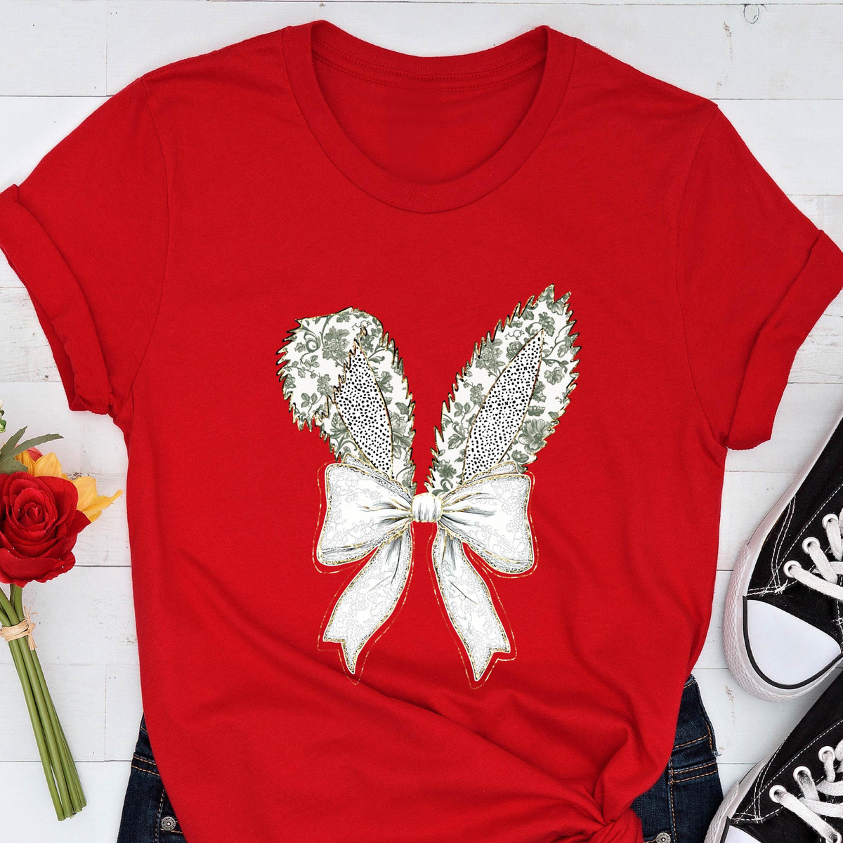 May include: Red t-shirt with a white bow and green floral bunny ears design.