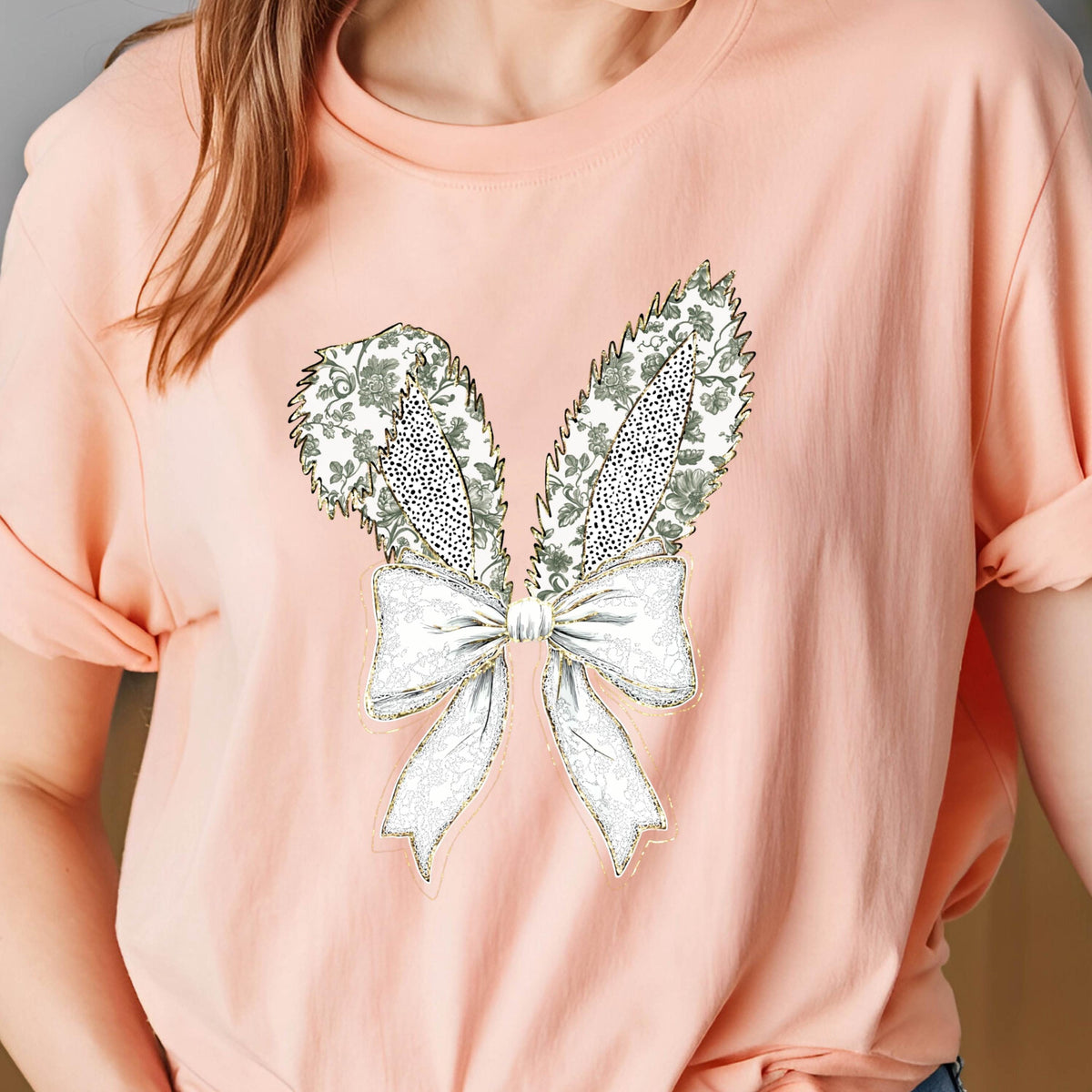 May include: A pink t-shirt with a white and green floral design in the shape of bunny ears with a white bow.