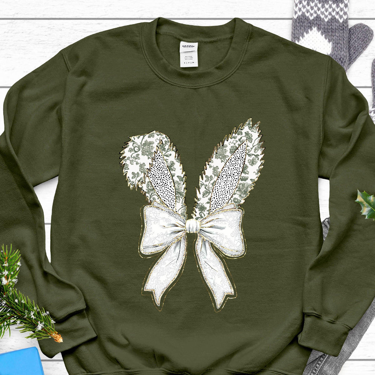 May include: A green sweatshirt with a white and gold bow and bunny ears design.