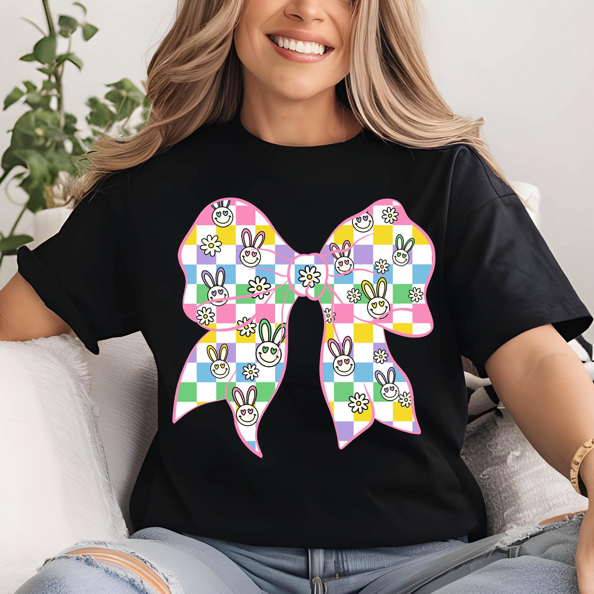 May include: Black t-shirt with a large pink bow. The bow is patterned with white squares, pink, green, yellow, and blue bunny faces with flowers.