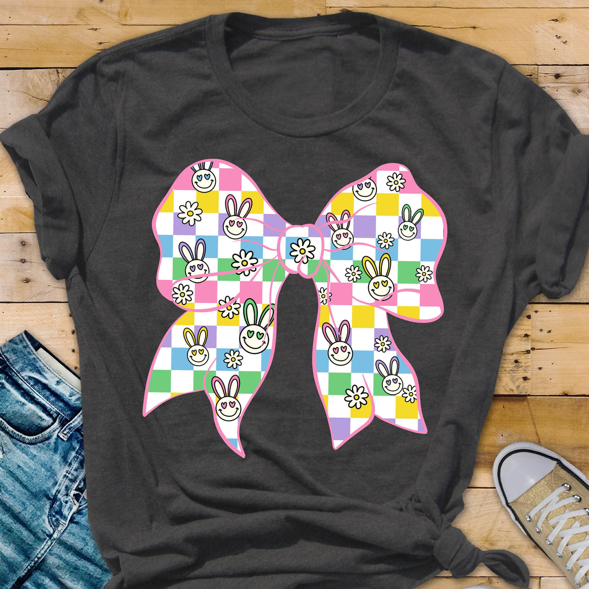May include: A gray t-shirt with a pink and white checkered bow. The bow is decorated with bunny faces and flowers in shades of pink, yellow, green, and purple.