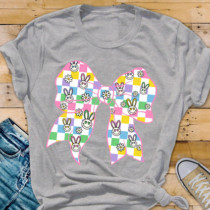 May include: A gray t-shirt with a pink bow featuring a checkered pattern with bunny faces and flowers. 